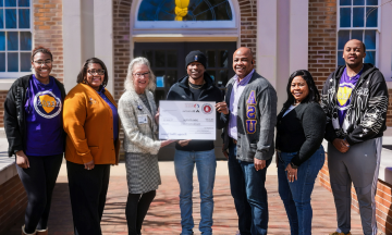 Jalen Phillips, an ASU senior, smiles and holds a large check for his $500 Regions Bank scholarship.